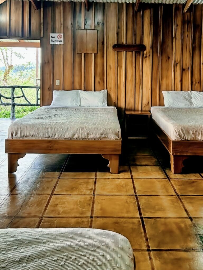 Cozy rustic bedroom at Casa Vista del Valle featuring three comfortable wooden beds, ideal for families or groups looking for an authentic farm stay near Arenal Volcano.